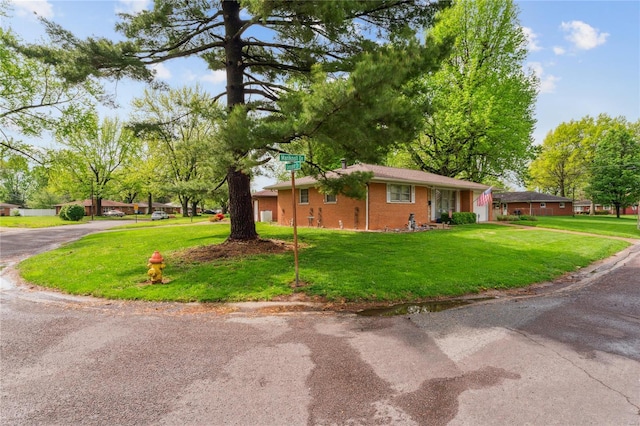 view of property exterior featuring a lawn, driveway, and brick siding