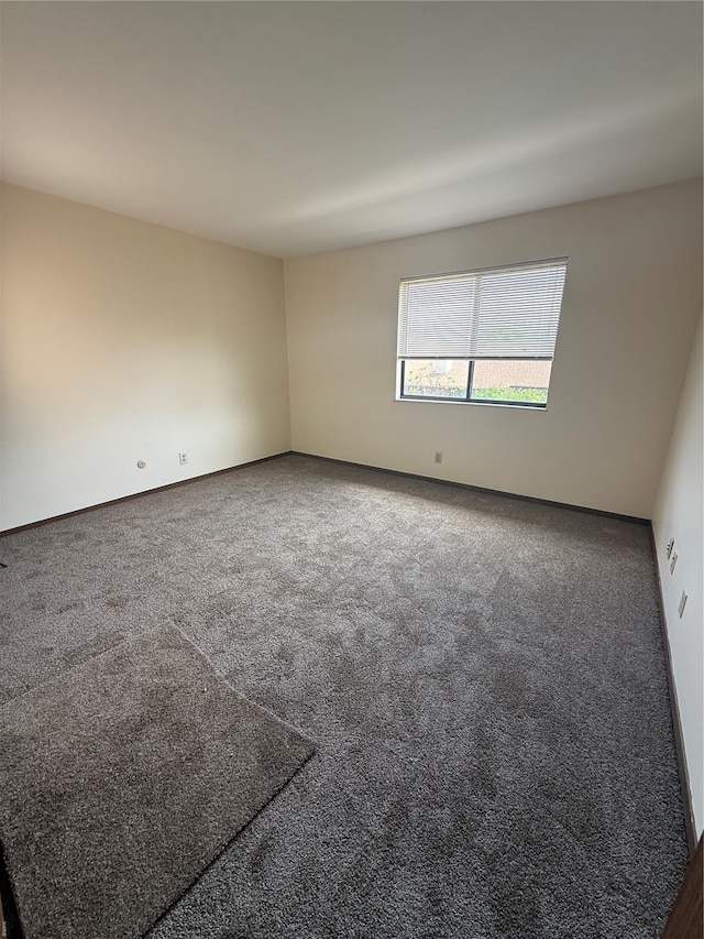 carpeted empty room featuring baseboards