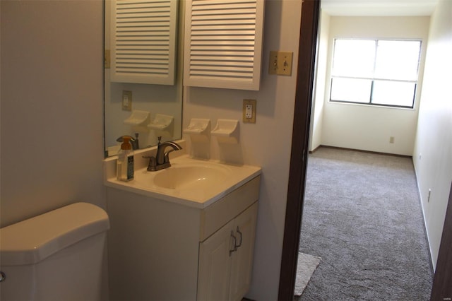 half bathroom with vanity, baseboards, and toilet