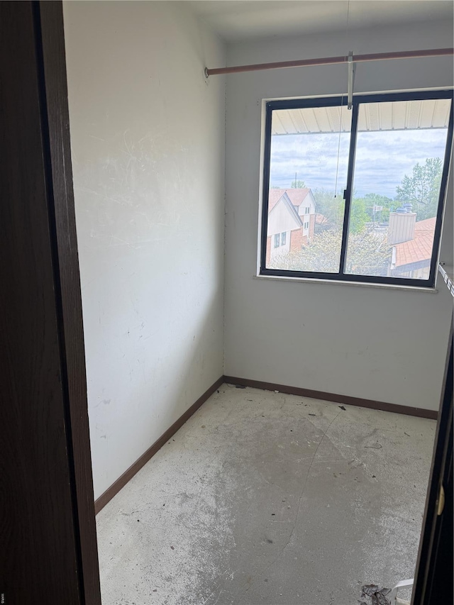unfurnished room with baseboards and unfinished concrete floors