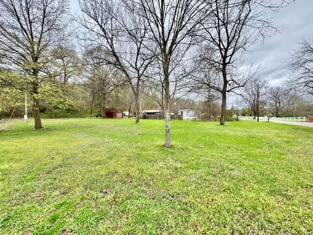 view of yard featuring fence, an outdoor structure, and a storage shed