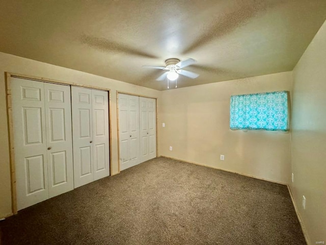 unfurnished bedroom featuring carpet floors, multiple closets, a textured ceiling, and baseboards
