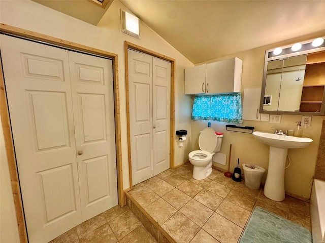 bathroom featuring tile patterned floors, vaulted ceiling, toilet, a sink, and a closet
