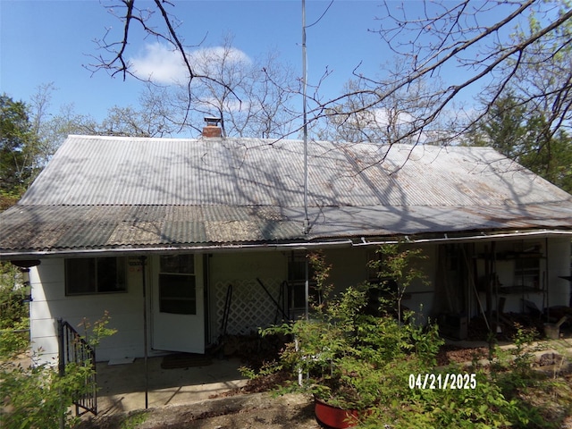back of property with a chimney and metal roof
