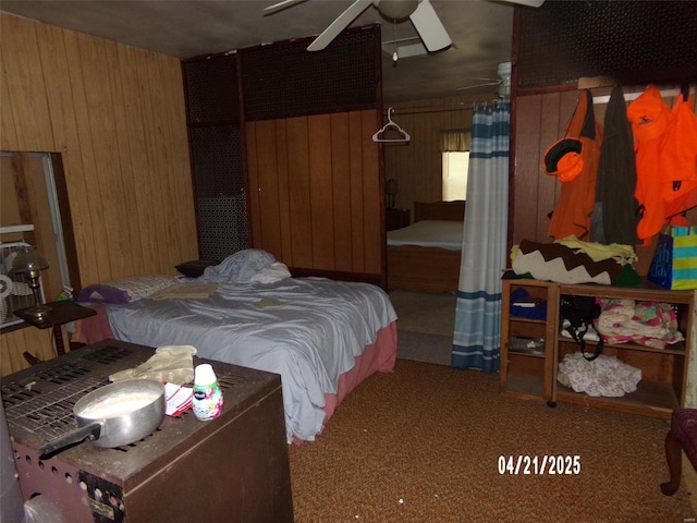 carpeted bedroom featuring a ceiling fan and wood walls