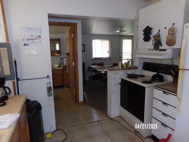 kitchen featuring under cabinet range hood, white appliances, and light tile patterned floors