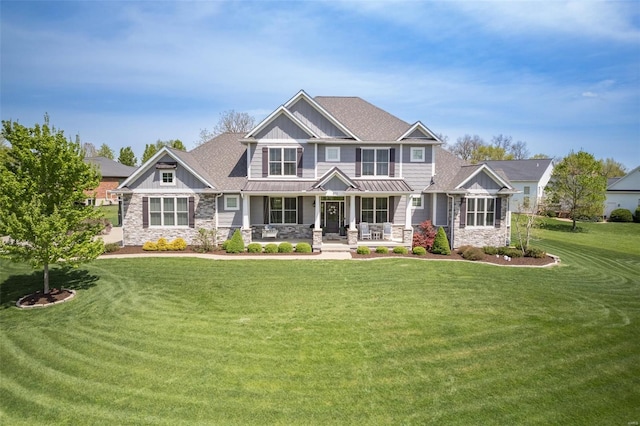 craftsman house featuring a front lawn, stone siding, a standing seam roof, and covered porch