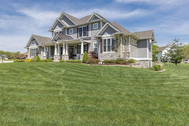 craftsman-style house featuring board and batten siding, stone siding, a front lawn, and covered porch
