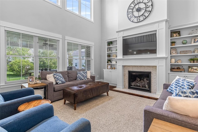 living room featuring built in shelves, a towering ceiling, and a fireplace
