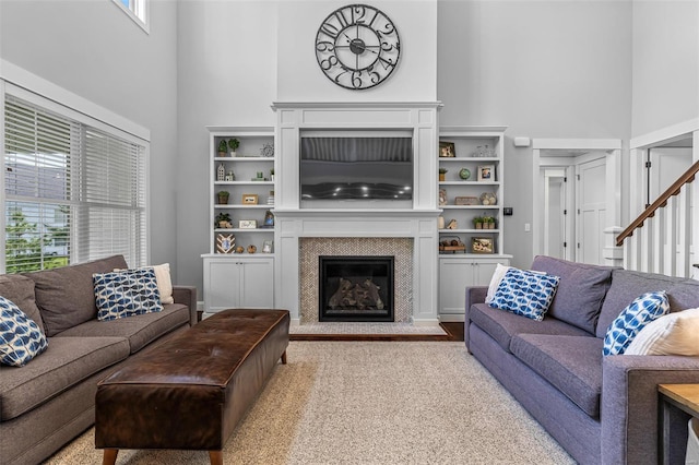 living area with a fireplace, stairway, and a towering ceiling