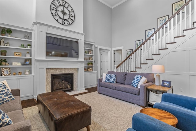 living area with a towering ceiling, a fireplace, stairway, and crown molding
