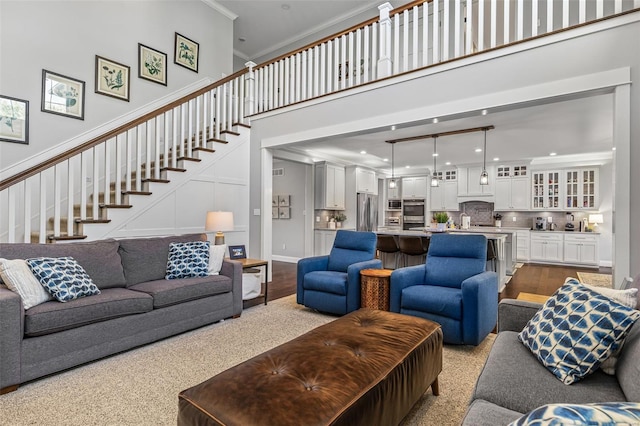 living room with recessed lighting, a towering ceiling, stairs, and ornamental molding