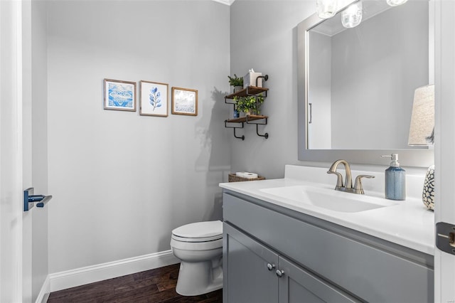 half bath with wood finished floors, vanity, toilet, and baseboards