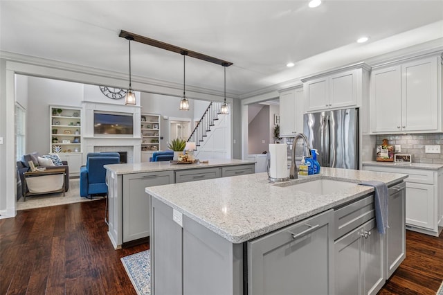 kitchen with open floor plan, freestanding refrigerator, a sink, and an island with sink