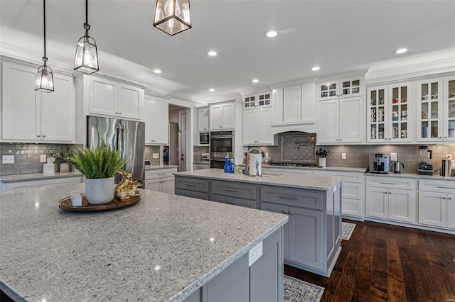 kitchen with white cabinetry, appliances with stainless steel finishes, and a center island with sink