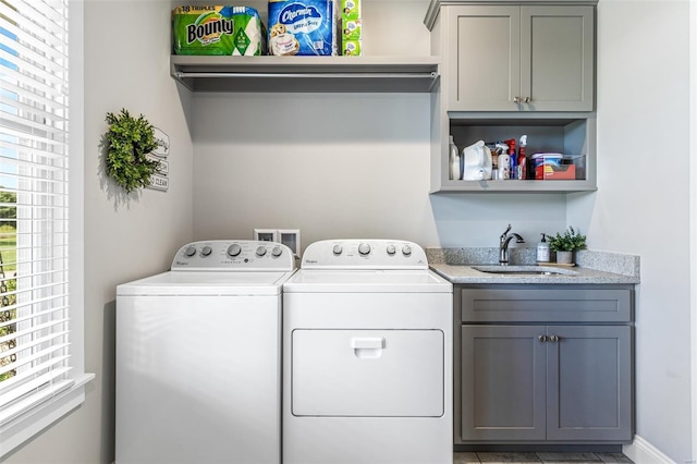 washroom with washer and dryer, cabinet space, and a sink