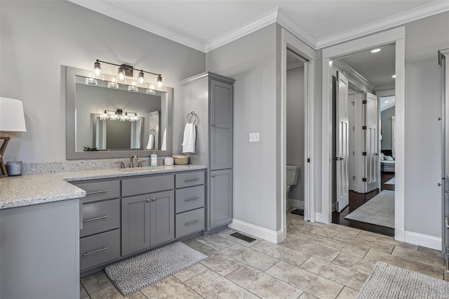 full bath featuring toilet, visible vents, baseboards, vanity, and ornamental molding