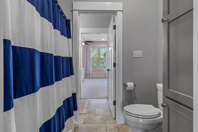 bathroom with toilet, baseboards, a ceiling fan, stone finish flooring, and a shower with shower curtain