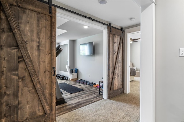 corridor featuring a barn door and carpet flooring