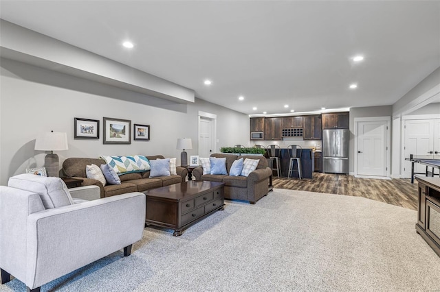 living area featuring wood finished floors, bar area, and recessed lighting