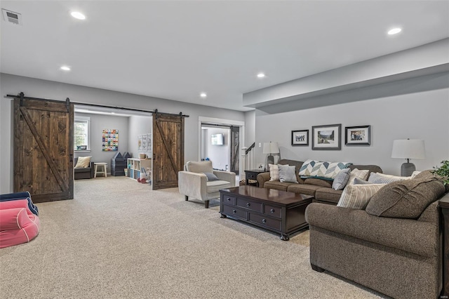 living room featuring a barn door, visible vents, light colored carpet, and recessed lighting
