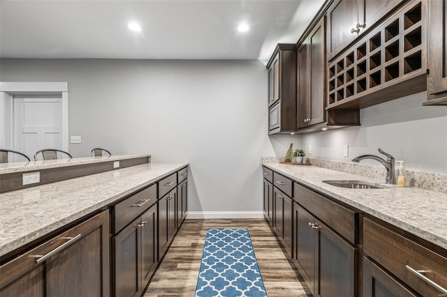 laundry room featuring recessed lighting, dark wood finished floors, baseboards, and a sink
