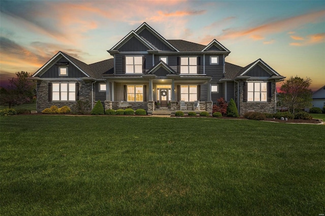 view of front of home featuring a yard, a porch, and stone siding