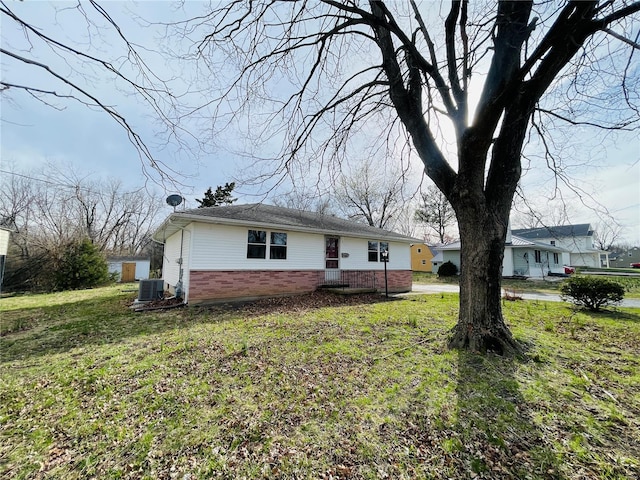 view of front of home with central AC, brick siding, and a front yard
