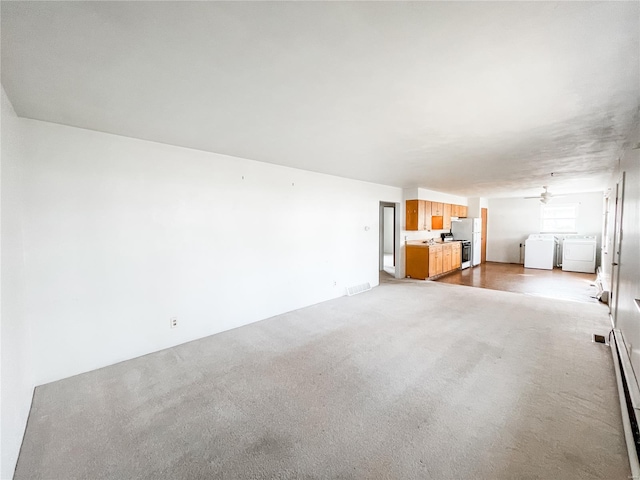 unfurnished living room featuring washer and clothes dryer, visible vents, carpet, ceiling fan, and a baseboard radiator