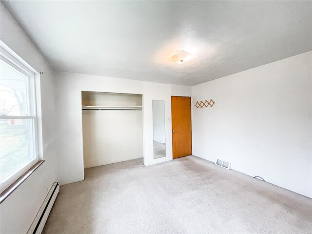 unfurnished bedroom with baseboard heating, visible vents, carpet floors, and a closet