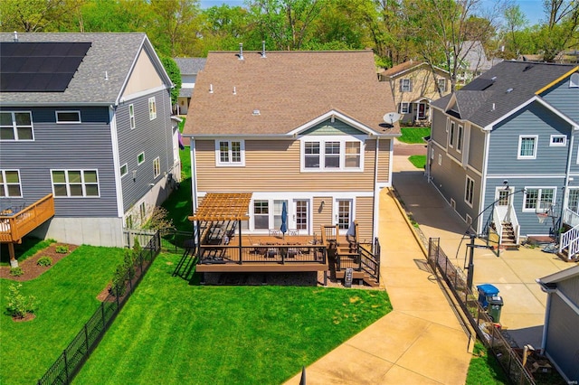 back of house featuring a fenced backyard, a wooden deck, a lawn, and a residential view