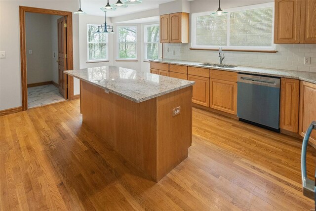 kitchen featuring stainless steel dishwasher, a center island, a sink, and light wood-style flooring