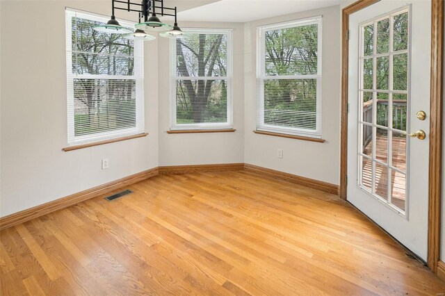unfurnished dining area featuring visible vents, light wood finished floors, and baseboards