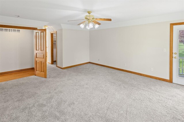 spare room with light carpet, a ceiling fan, visible vents, and baseboards