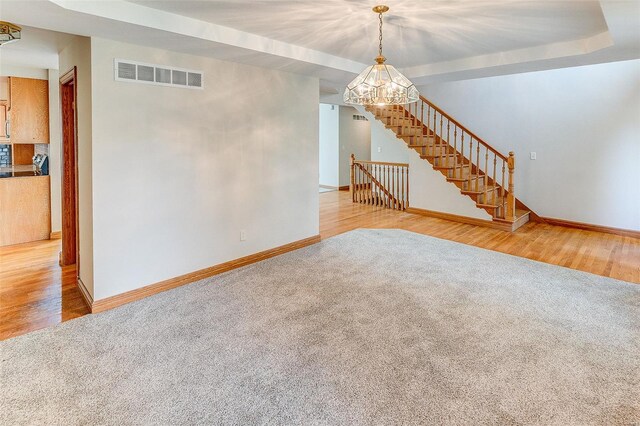 unfurnished living room featuring a chandelier, carpet, visible vents, and baseboards