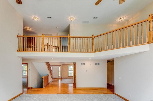 unfurnished living room with a towering ceiling, stairs, and visible vents