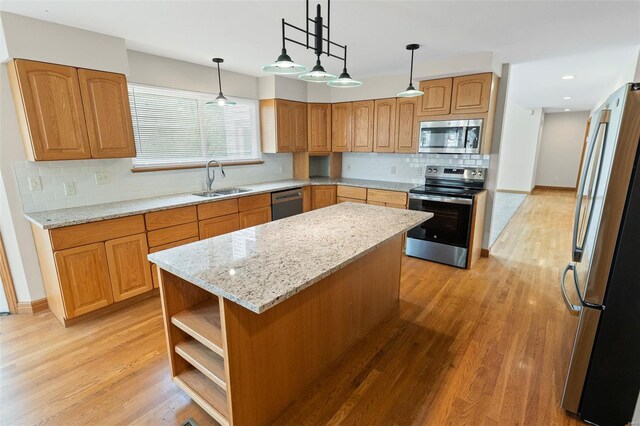 kitchen featuring stainless steel appliances, light wood-style flooring, a sink, tasteful backsplash, and light stone countertops