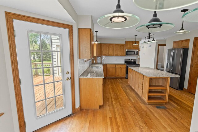 kitchen with stainless steel appliances, a sink, light wood-type flooring, light stone counters, and open shelves