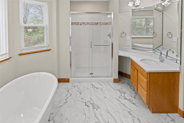 full bath with a shower stall, marble finish floor, vanity, baseboards, and a soaking tub