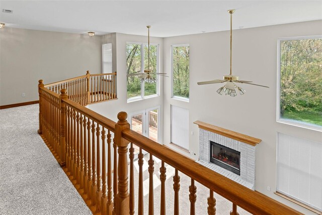 corridor featuring carpet, baseboards, plenty of natural light, and an upstairs landing