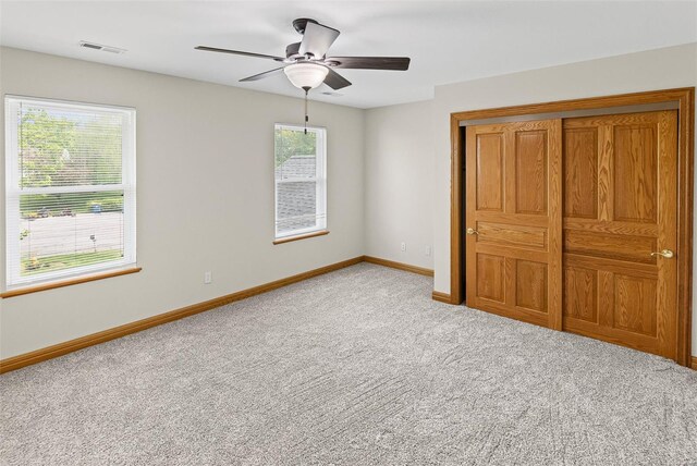 unfurnished bedroom with a ceiling fan, a closet, light colored carpet, baseboards, and visible vents