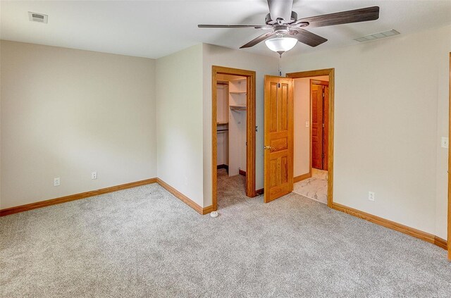 unfurnished bedroom with a walk in closet, baseboards, visible vents, and carpet flooring