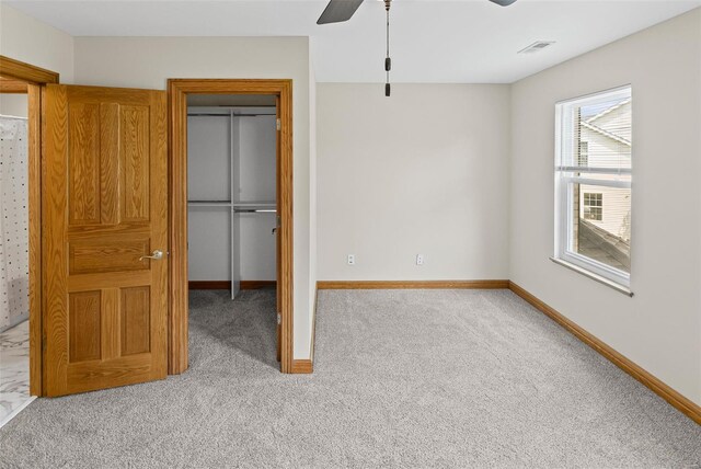 unfurnished bedroom featuring a closet, ceiling fan, carpet floors, baseboards, and visible vents
