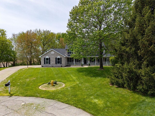 view of front of home with driveway, a front lawn, and covered porch