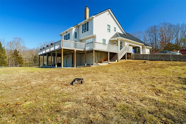 rear view of house featuring a deck, a chimney, a yard, stairway, and fence
