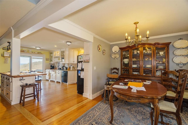 dining space featuring an inviting chandelier, crown molding, light wood finished floors, and baseboards