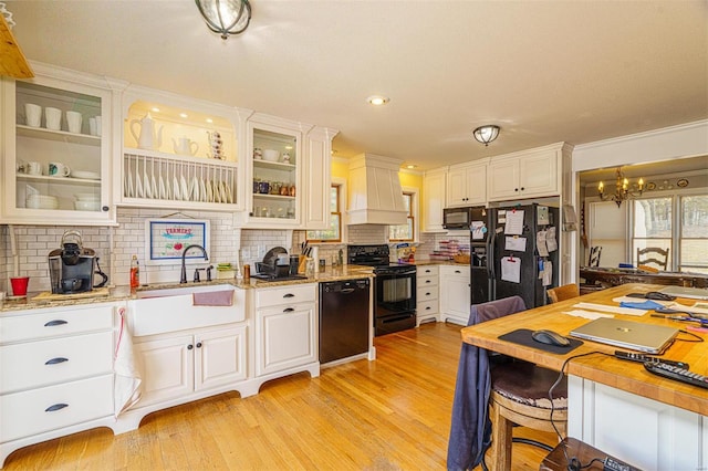 kitchen with white cabinetry, black appliances, light wood finished floors, custom exhaust hood, and backsplash
