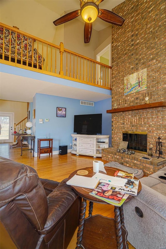 living room with stairway, wood finished floors, ceiling fan, and a high ceiling