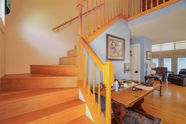 stairway featuring a towering ceiling and wood finished floors