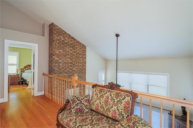 corridor featuring baseboards, high vaulted ceiling, and wood finished floors
